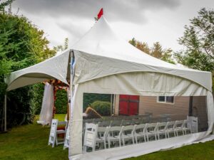 Backyard wedding tent rental with white folding chairs